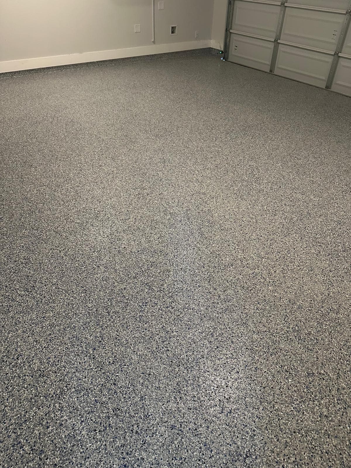 The same floor at standing height, showing off-white, grey and navy flake locked under a clear topcoat with an even, closed surface.