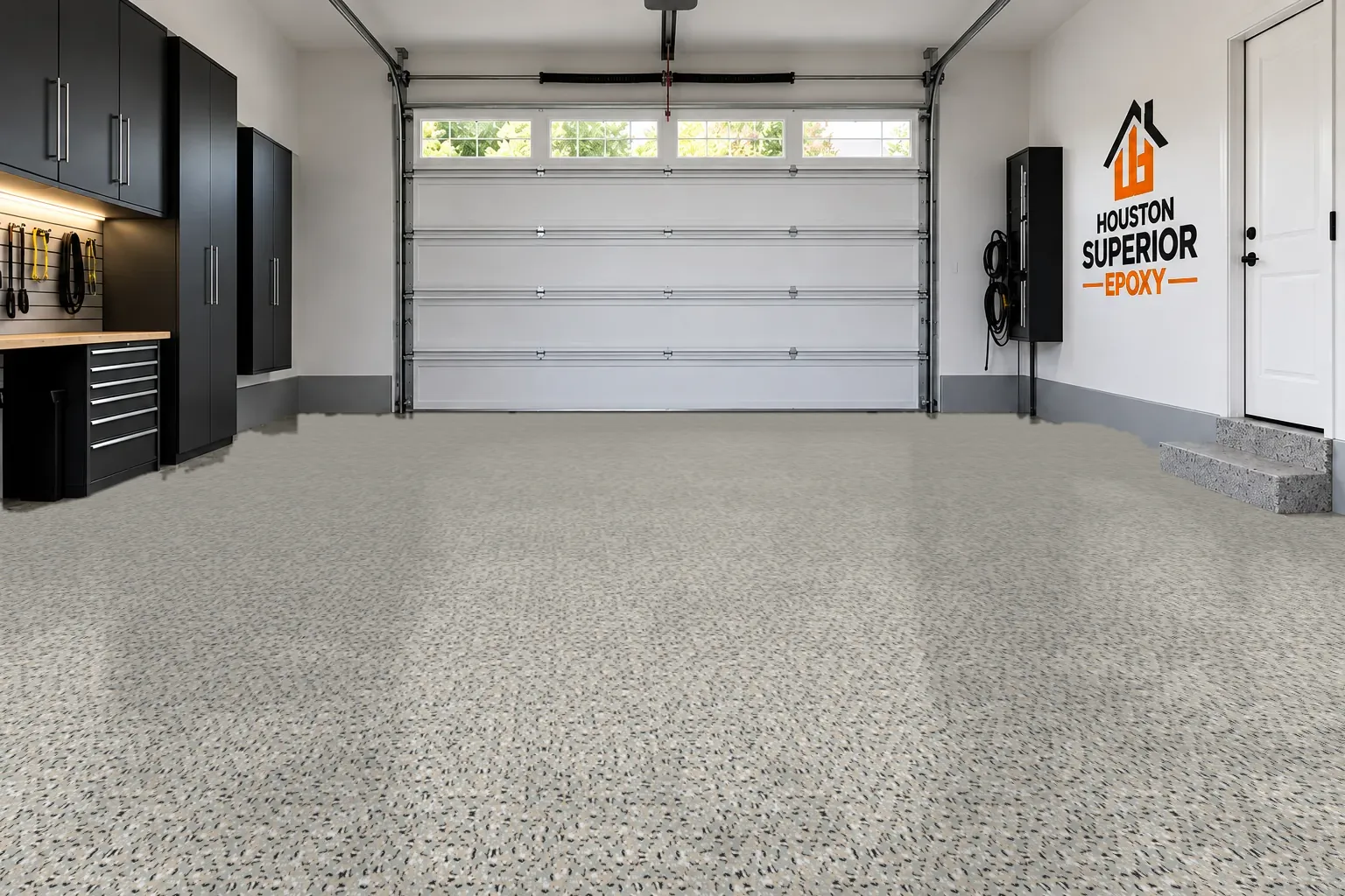 A two-car garage with its floor finished in the Cabin Fever flake blend, viewed from the back wall toward the closed door.